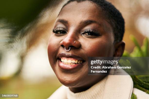 african american woman with a septum piercing smiling while looking at camera in the park - septum stock pictures, royalty-free photos & images