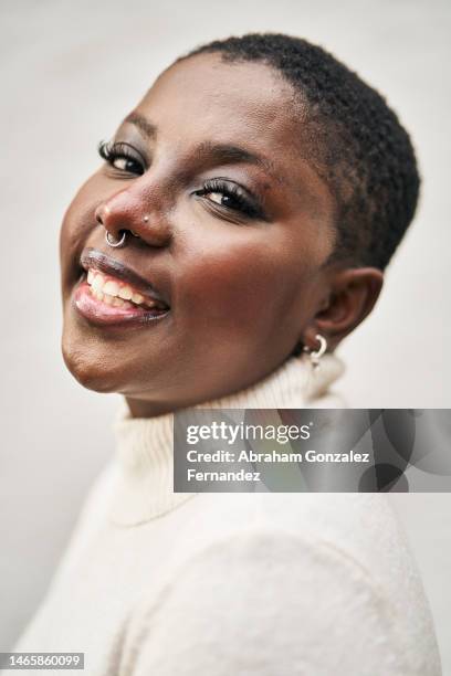 young african american woman with short curly hair and piercings looking at camera outdoors - piercing stock-fotos und bilder