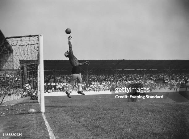 British footballer Lawrie Leslie, West Ham goalkeeper, stretches to tip the shot over the bar during the English League Division One match between...