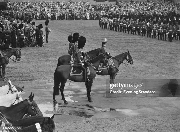 British Royals Prince Philip, Duke of Edinburgh , wearing a Guardsman's uniform with a bearskin hat, and his wife, Queen Elizabeth II, wearing a...