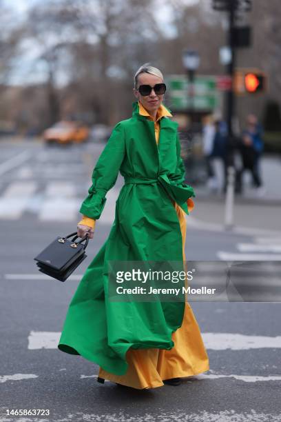 Denisa Palsha wearing Carolina Herrera green oversized coat, Brandon Maxwell yellow jumpsuit, Schiaparelli black leather bag before Carolina Herrera...
