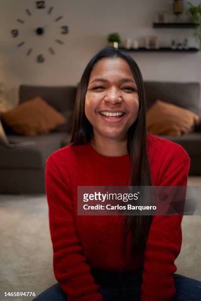 cheerful woman looking at camera smiling, while sitting on the ground in the living room at home. - ladies day stock pictures, royalty-free photos & images