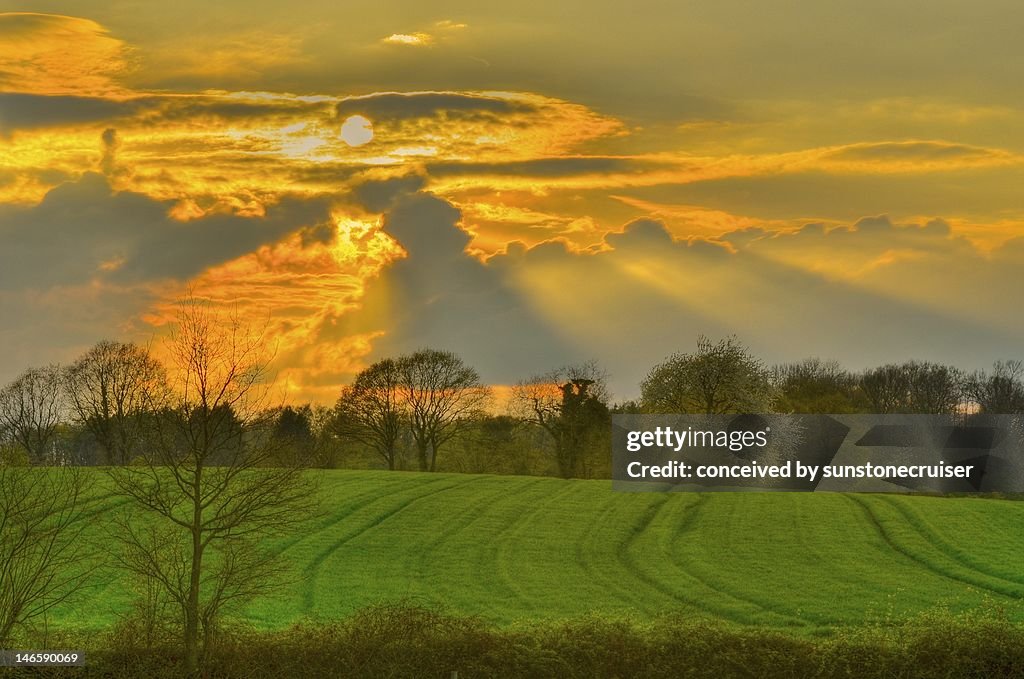 Zondsondergang met zonnestralen door de wolken