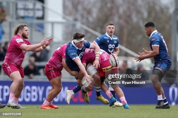 Alex Groves of Sale Sharks offloads the ball to Tristan Woodman whilst being tackled by Rus Tuima and Santiago Grondona of Exeter Chiefs during the...