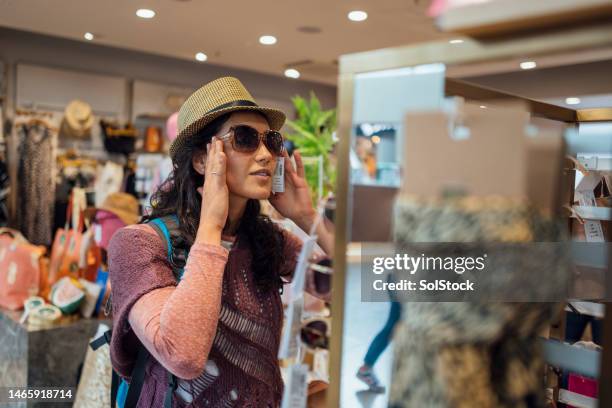 choosing sunglasses for her hols - airport shopping stockfoto's en -beelden