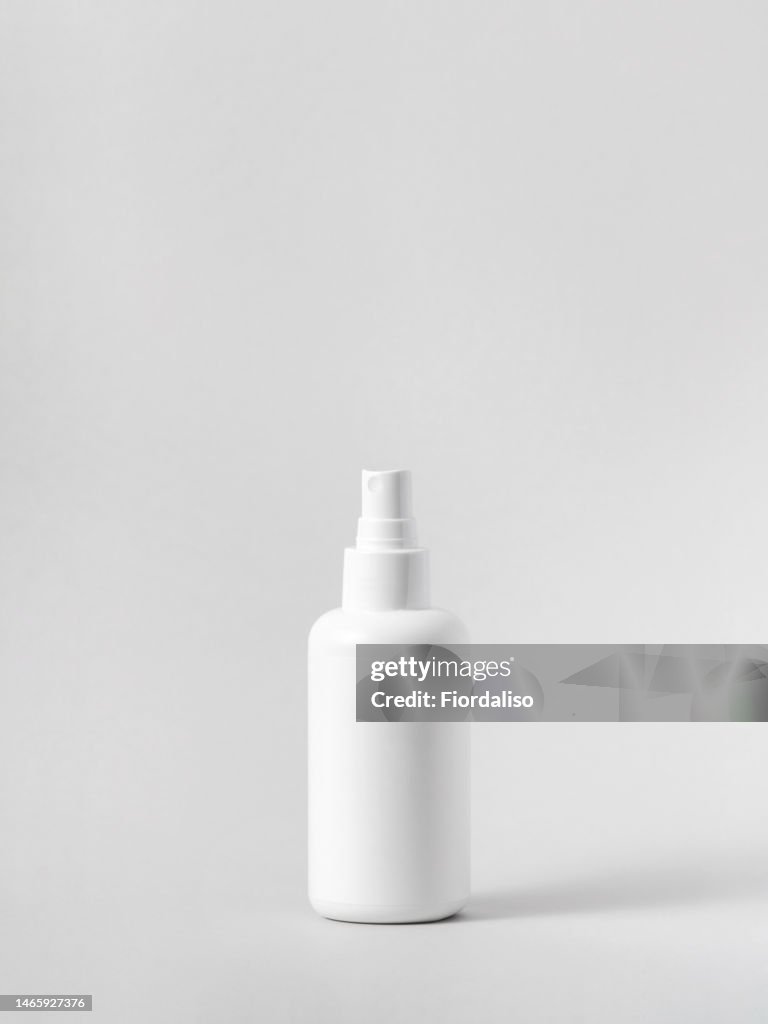 White plastic bottle with dispenser, spray for face, body, scalp care on a light gray background