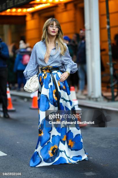 Guest wears glasses, gold earrings, gold chain necklaces, a navy blue and white striped print pattern / puffy long sleeves shirt, a black shiny...
