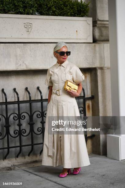 Grece Ghanem wears black with white rhinestones squared sunglasses, a beige short sleeves long pleated dress, a gold shiny leather handbag from...