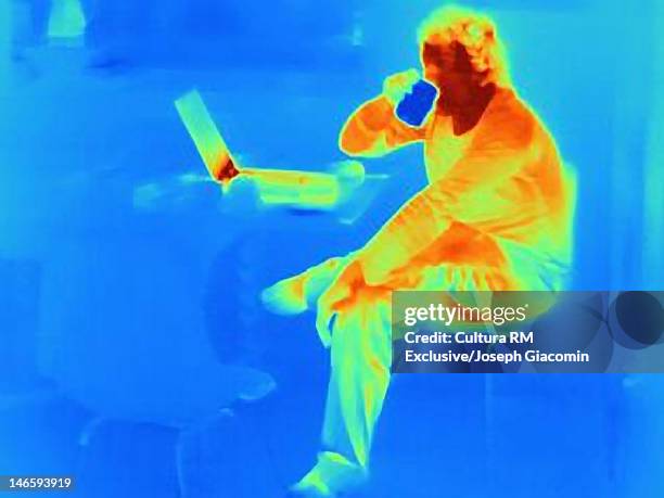 thermal image of man with coffee at laptop - thermo becher stock-fotos und bilder