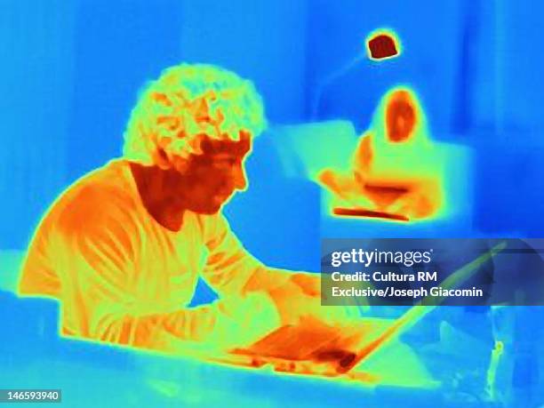 thermal image of man using laptop at table - wärmebild stock-fotos und bilder