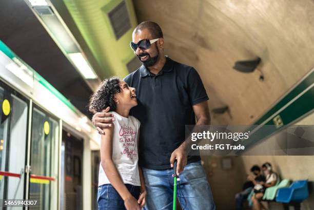 blind father and daughter talking while walking at a subway station - blind girl stock pictures, royalty-free photos & images