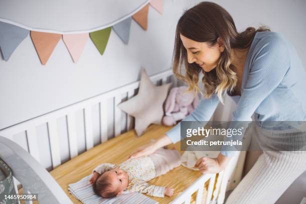 mother with her cute baby girl in her crib - baby crib stockfoto's en -beelden