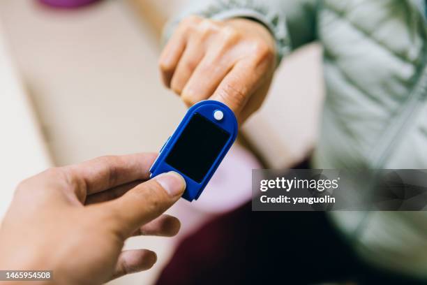 middle aged women use finger pulse oximeter to check their physical condition - healthy lifestyle, health and medical treatment - finger tablet stock pictures, royalty-free photos & images
