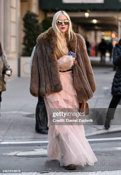 Guest is seen wearing a Dennis Basso pink dress and a faux fur coat outside the Dennis Basso show during New York Fashion Week F/W 2023 on February...