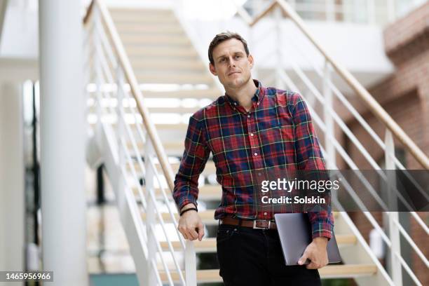 male teacher standing on school hallway stairs - teachers unions foto e immagini stock
