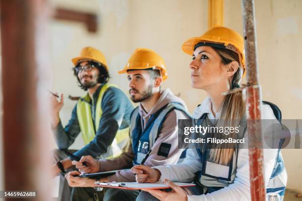 three people are listening to their foreman on a construction site - educational facility stock pictures, royalty-free photos & images