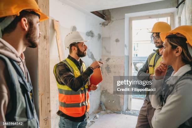 a man is explaining the project to three workers / students - apprentice builder stock pictures, royalty-free photos & images