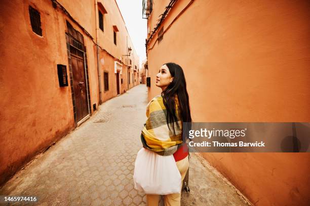 wide shot of woman exploring the medina of marrakech while on vacation - morrocco stock-fotos und bilder