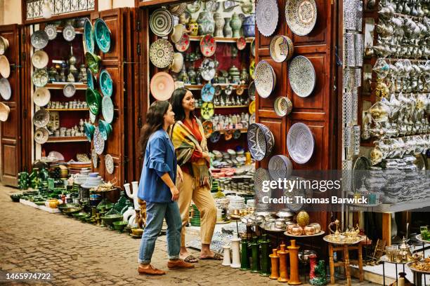 wide shot of friends exploring and shopping in the souks of marrakech - soek stockfoto's en -beelden