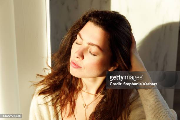 portrait of young woman on sunny day with shade on her face brunette real person - mottled skin stockfoto's en -beelden