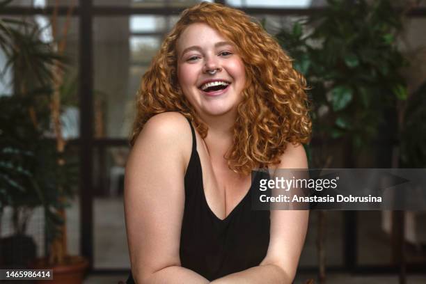 portrait of an attractive and voluptuous young woman posing in background in studio - fat redhead stock pictures, royalty-free photos & images