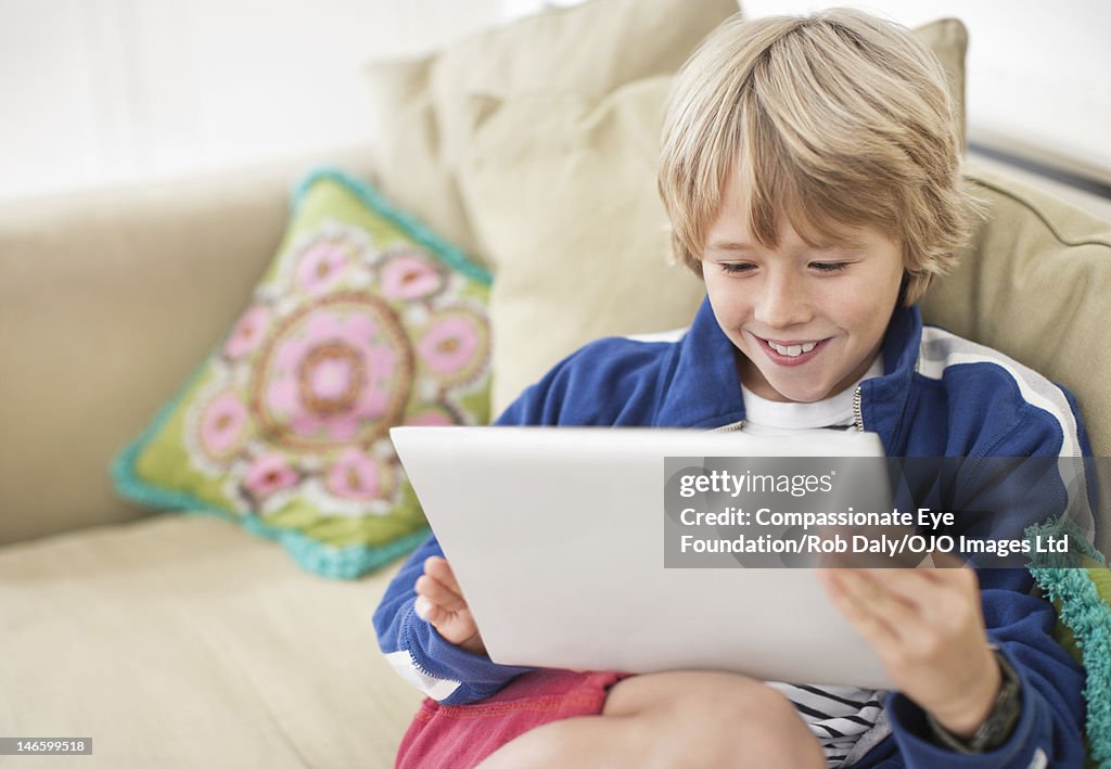 Boy (9-10) using digital tablet in living room