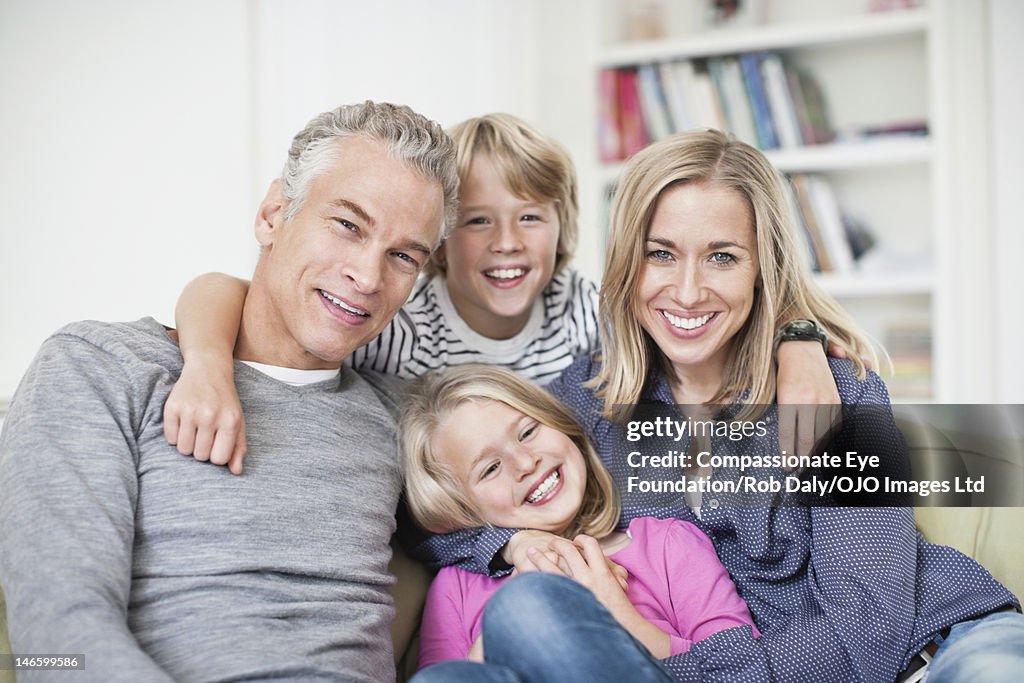 Family sitting on sofa, smiling