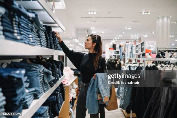 woman shopping denim jeans in a clothing store - retail shop bildbanksfoton och bilder