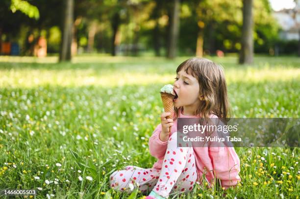 little girl with ice cream in park. - girl eating messy ice cream cone stock pictures, royalty-free photos & images