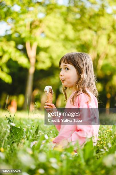 kleines mädchen, das spaß daran hat, die süße eistüte im freien zu genießen. - girl eating messy ice cream cone stock-fotos und bilder