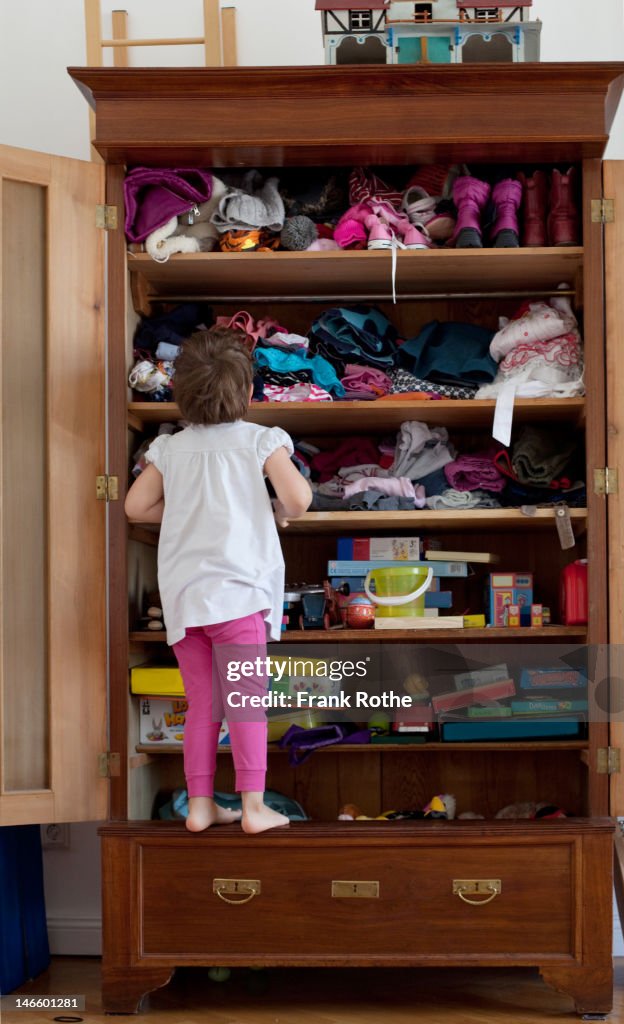 A young kid in front of here closet searching