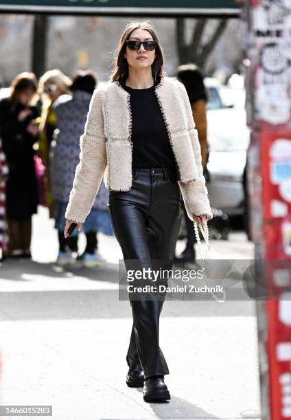 Guest is seen wearing a cream faux fur Coach jacket, black sweater and leather pants with white bag outside the Coach show during New York Fashion...