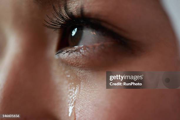 young woman with tear rolling down cheek - tearing stock pictures, royalty-free photos & images