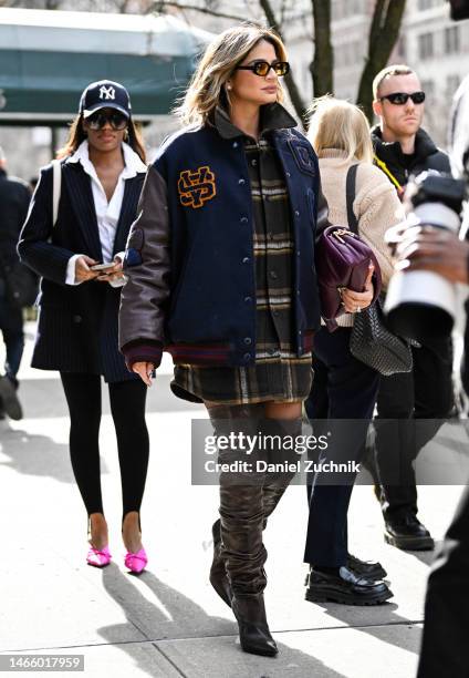 Thassia Naves is seen wearing a Coach varsity jacket, plaid shirt and brown leather boots with a Coach bag outside the Coach show during New York...