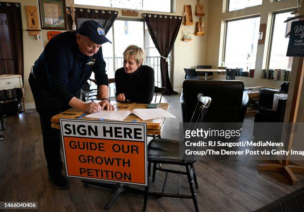 Timnath resident Clifford Nancarrow, left, signs a petition collecting signatures for a ballot measure that will ban 65 foot tall fences on February...