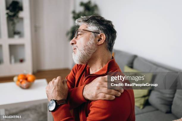 mature man having problems with joints - smart glasses stockfoto's en -beelden