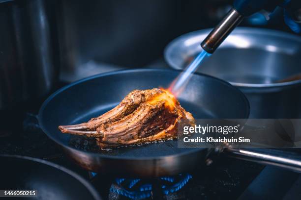 blowtorch flame on pan grilled steak close up - gourmet stock-fotos und bilder