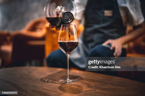 pouring red wine into wine glass from decanter - kurkentrekker drankenbenodigdheden stockfoto's en -beelden