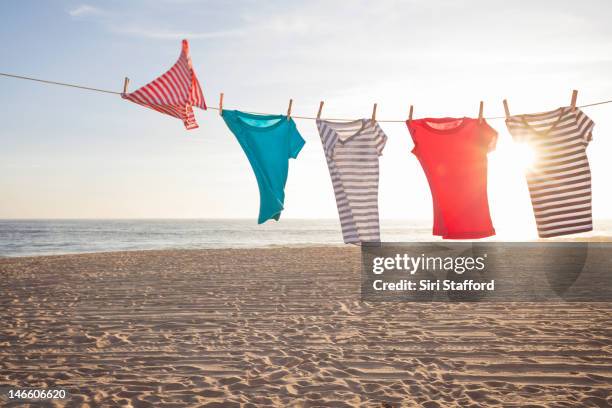 t-shirts on a clothesline at a beach - beach solar laundry stock pictures, royalty-free photos & images