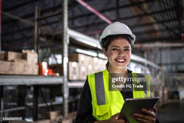portrait of a young woman working on a digital tablet in a warehouse - gender equality stock pictures, royalty-free photos & images