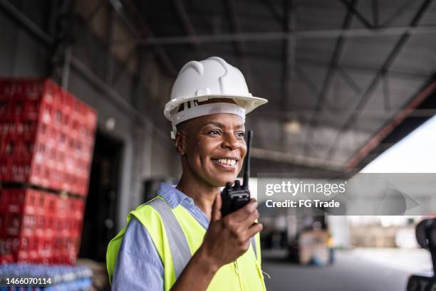 mature woman talking on a walkie-talkie in a warehouse - walkie talkie stock pictures, royalty-free photos & images