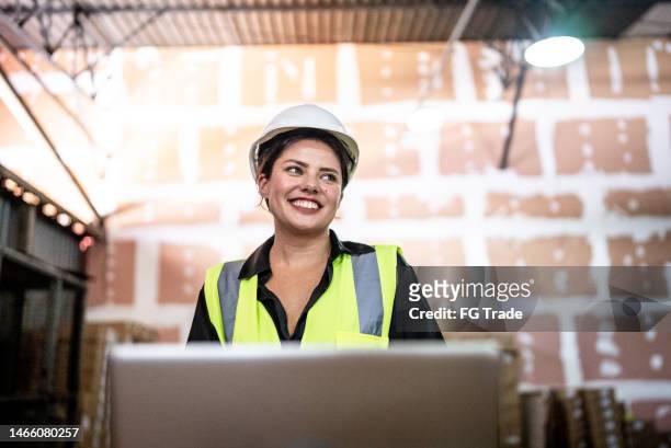 young woman working on the laptop in a warehouse - female builder stock pictures, royalty-free photos & images