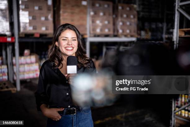 reporter talking on a microphone in a warehouse - photographic equipment stock pictures, royalty-free photos & images