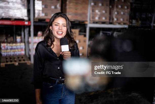 reporter talking on a microphone in a warehouse - tv reporter 個照片及圖片檔