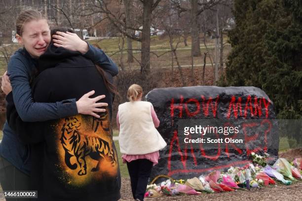 People leave flowers, mourn and pray at a makeshift memorial at "The Rock" on the campus of Michigan State University on February 14, 2023 in East...