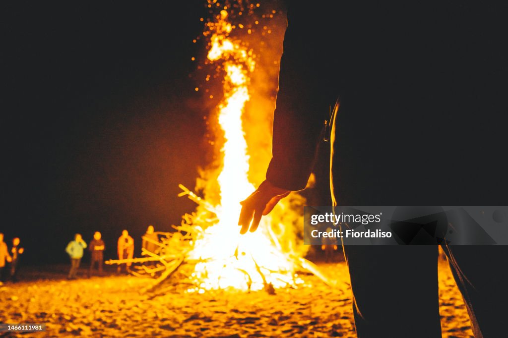 Big bonfire in the night, flames of fire, sparks. Rituals, circle magic, round dance, selective focus