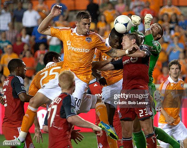 Je-Vaughn Watson of the Houston Dynamo and Geoff Cameron and Terry Dunfield of the Toronto FC get their heads on the ball as goalkeeper Milos Kocic...