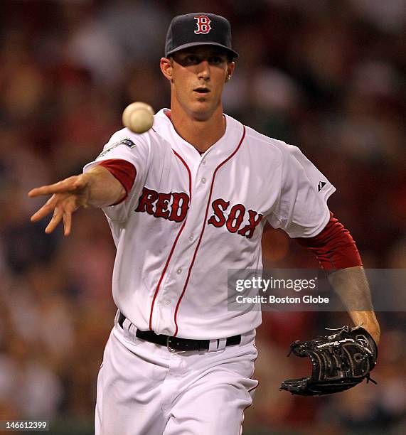 Boston Red Sox relief pitcher Clayton Mortensen underhands the throw to first base for the out in the eighth inning as the Boston Red Sox took on the...