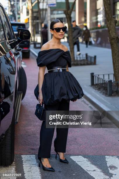 Lea Michele wears black pleated off shoulder dress with zipper, black pants, sunglasses outside Brandon Maxwell during New York Fashion Week on...