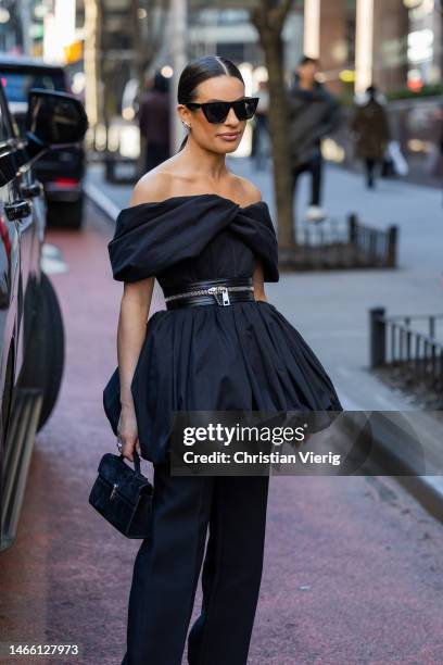 Lea Michele wears black pleated off shoulder dress with zipper, black pants, sunglasses outside Brandon Maxwell during New York Fashion Week on...